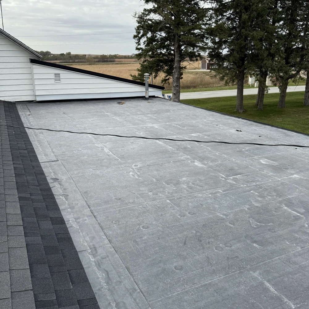 Roofer applying EPDM bonding adhesive on Mason City Iowa flat roof